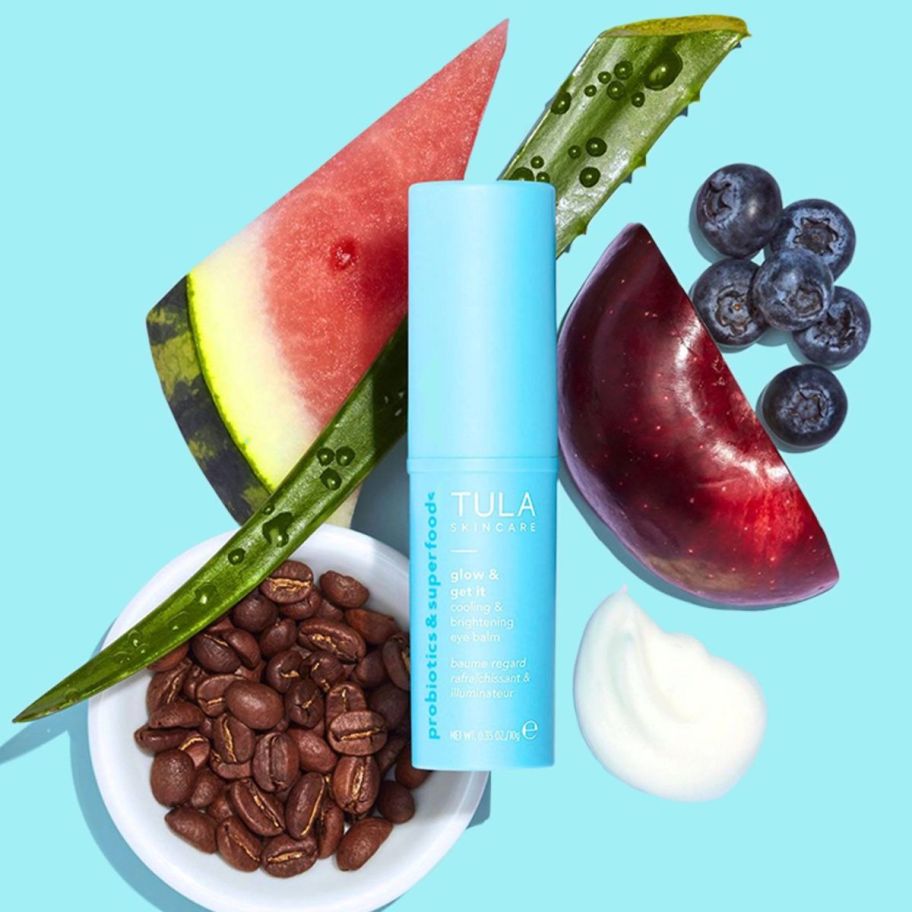 a bottle of tula eye balm surrounded by fruits