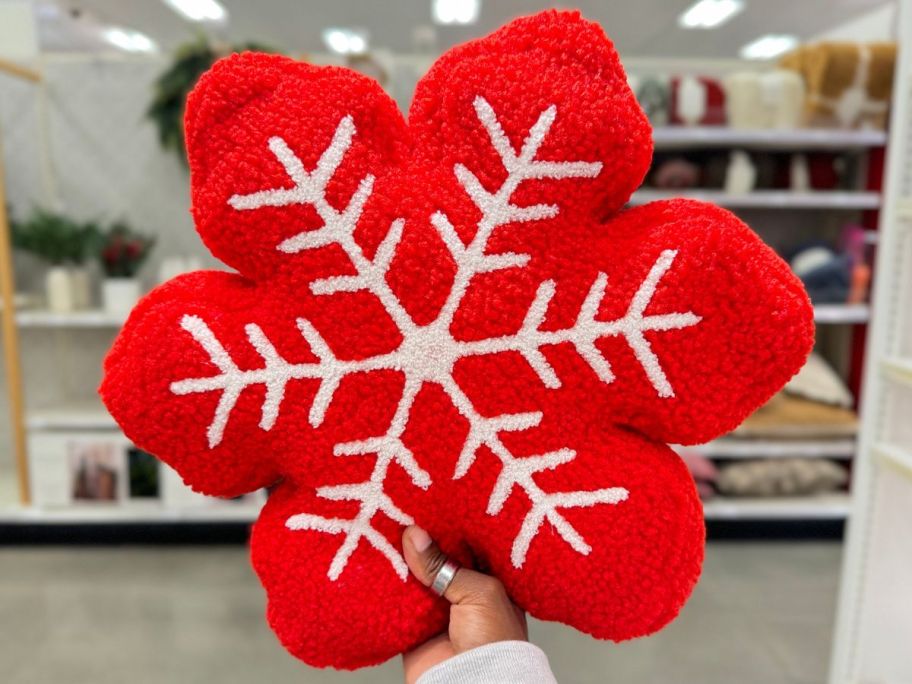 Hand holding up a Threshold Red Snowflake Shaped Throw Pillow