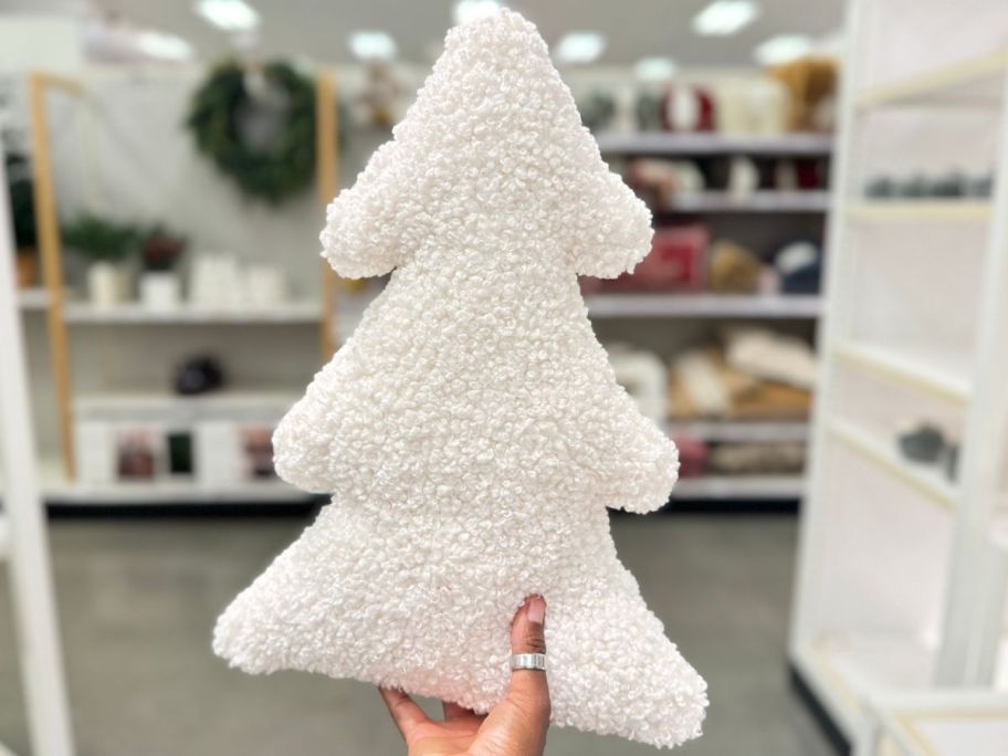 Hand holding up a Threshold Throw pillow that looks like a holiday tree