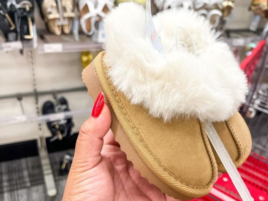 A person holding up a child's slipper in a store