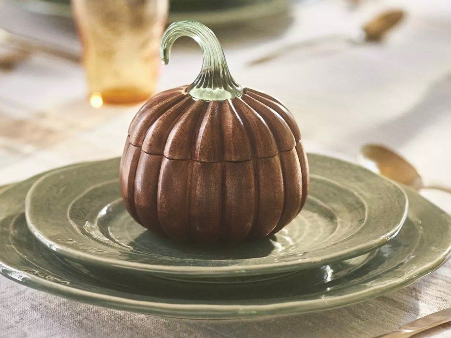 pumpkin candle sitting on green plate on table