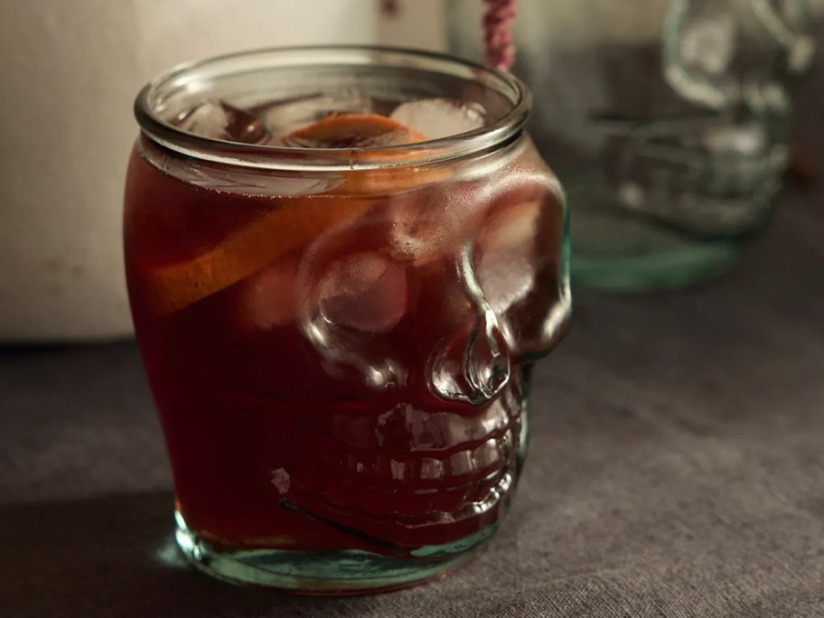 skull tumbler with red drink inside on table