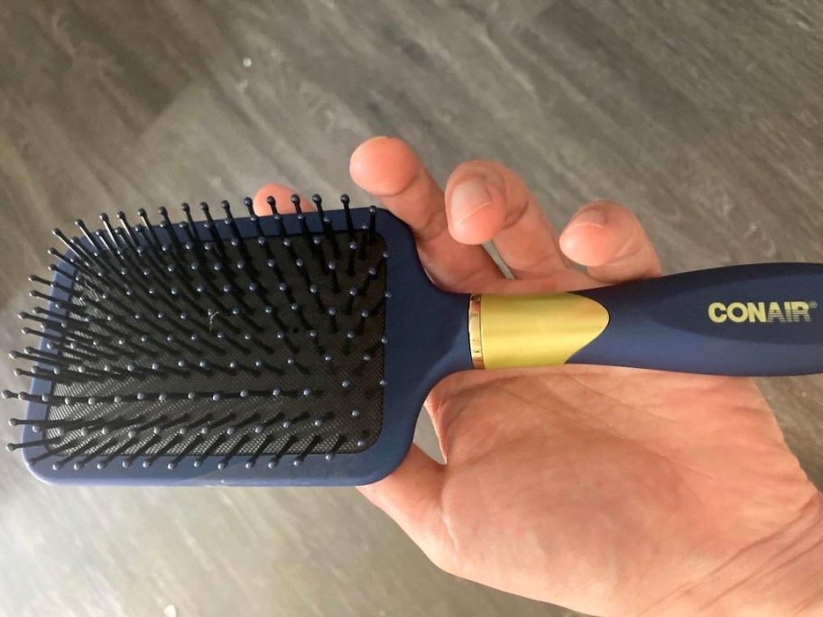 hand holding a blue hairbrush