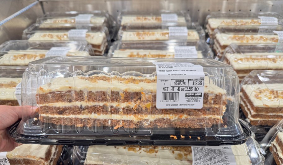 costco carrot cake in plastic packaging held in front of a store display
