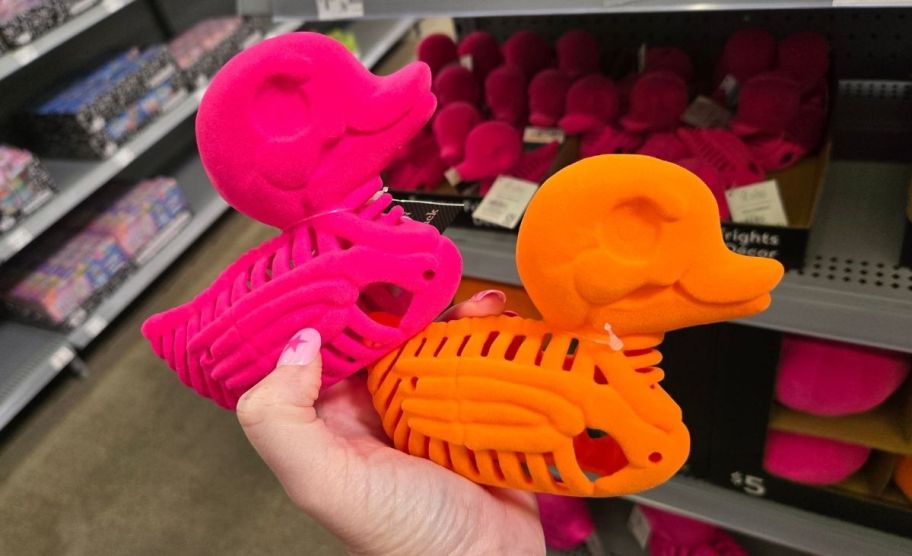 a woman's hand holding tow neon colored felt ducks