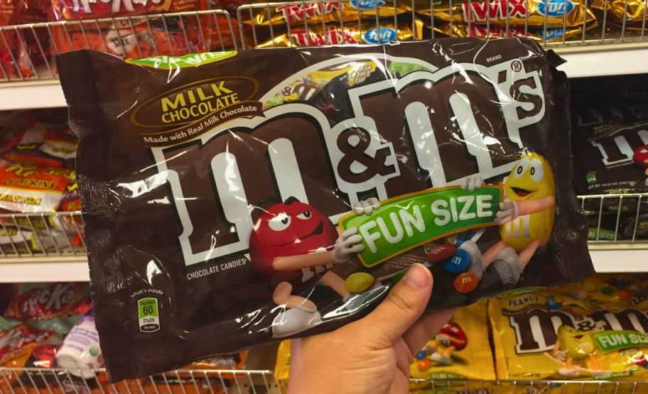 a womans hand holding a bag of fun size mms