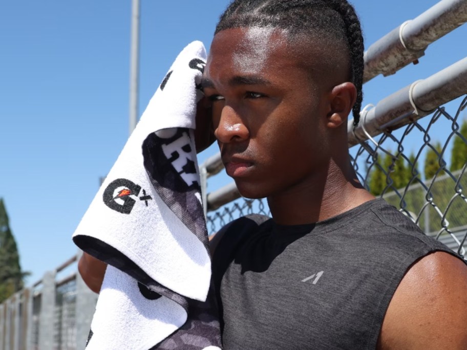 man using a black and white Gatorade GX towel to wipe sweat - he looks like an athlete