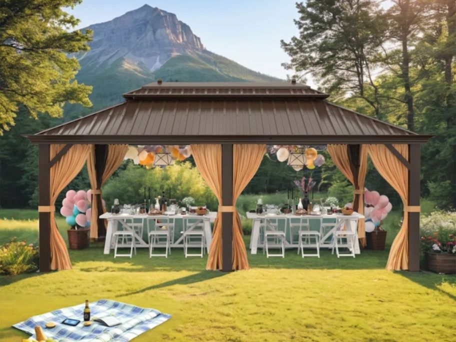 beige and brown gazebo with table and chairs underneath on grass
