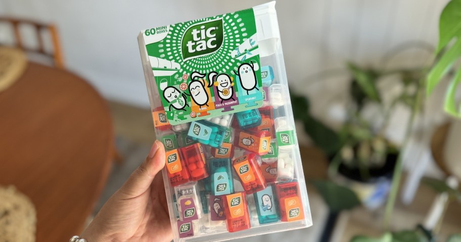 hand holding a giant Tic Tac candy container filled with mini Tic Tac candy continers