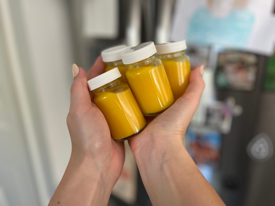 hand holding mini glass bottle with orange colored juice