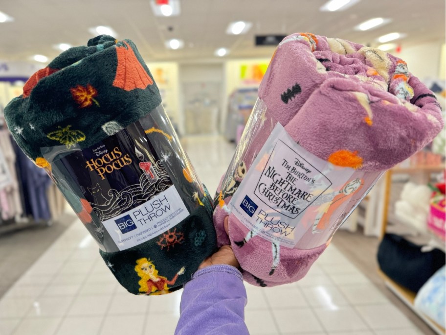 hand holding up Disney Hocus Pocus and Nightmare Before Christmas plush blanket throws in a store