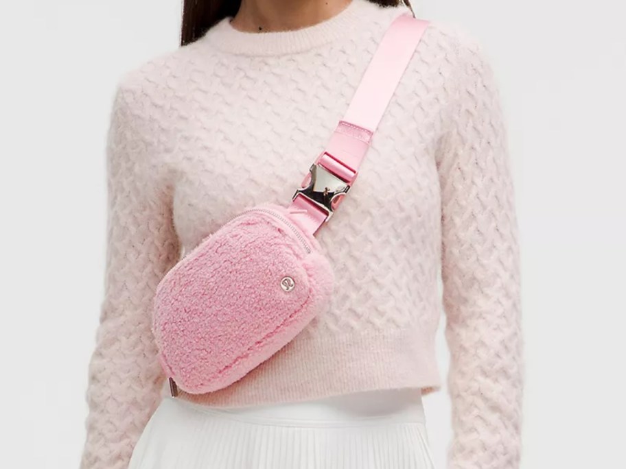 woman wearing a pale pinkish cream sweater with a light pink fleece belt bag as a cross body bag