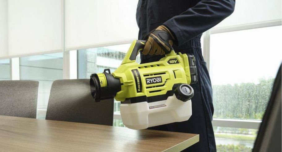 person using sprayer tool on table