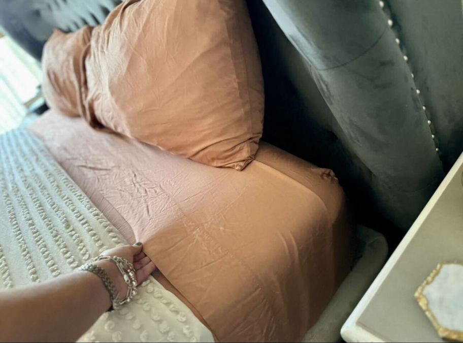 hand holding edge of clay bedsheet on bed