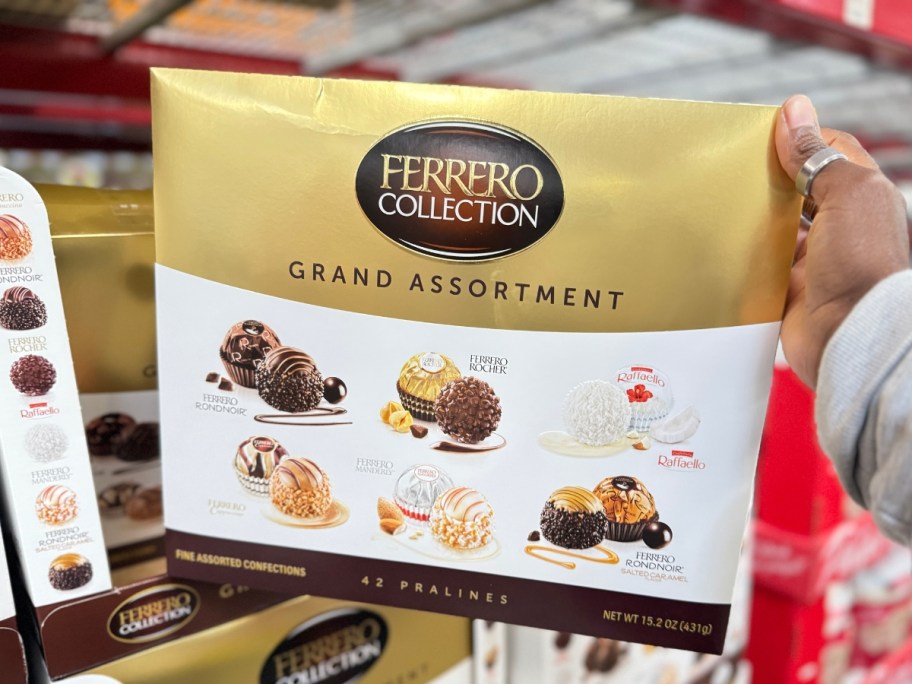 hand holding a gold and white box of Ferrero Rocher candies in store 