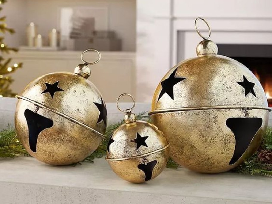 three gold metal jingle bells of varying sizes on display on a table in a home