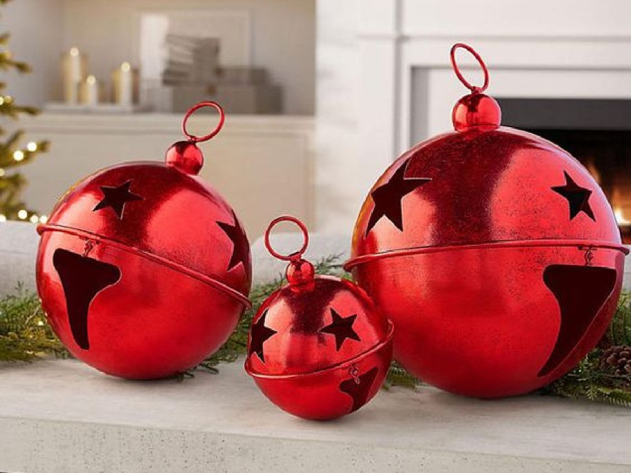 three red metal jingle bells of varying sizes on display on a table in a home