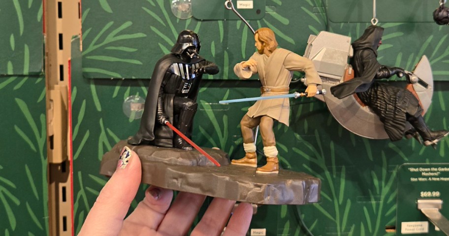 hand holding darth vader and obi wan ornament