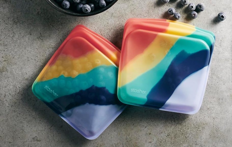 two rainbow stasher bags with blueberries on concrete counter