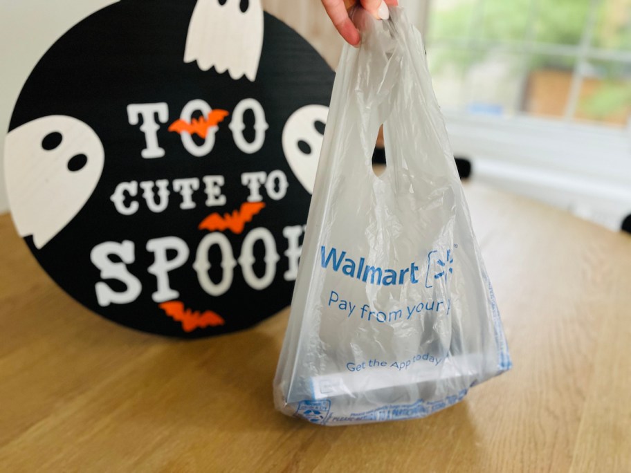 hand holding up walmart bag with halloween too cute to spook sign