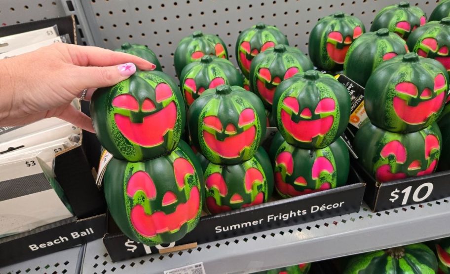 a woman's hand holding a watermelon jack o lantern stack