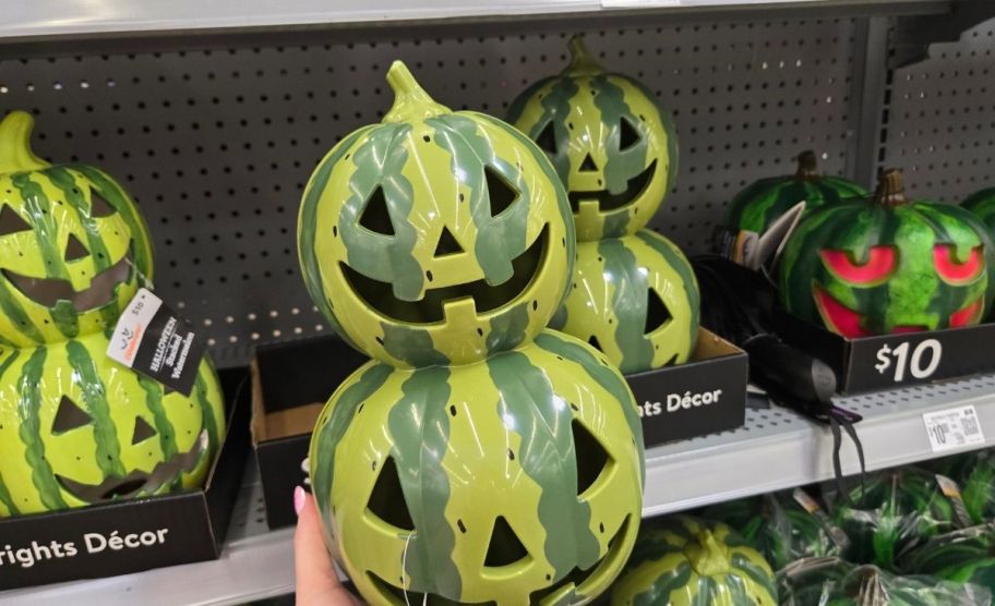 a woman's hand holding a watermelon jack o lantern stack