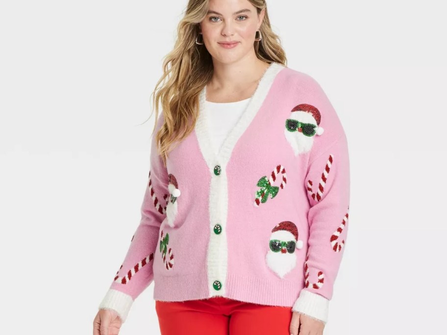 woman wearing a pink button up cardigan with Santa, and candy canes on it