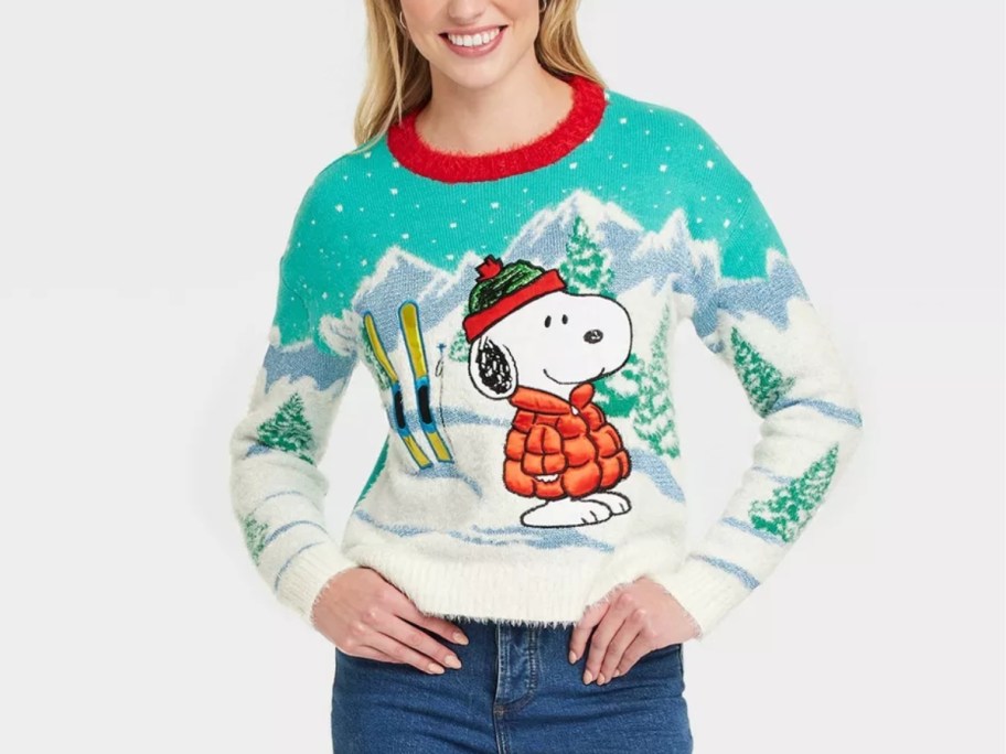 woman wearing a sweater with Snoopy in a snowy winter ski scene on it