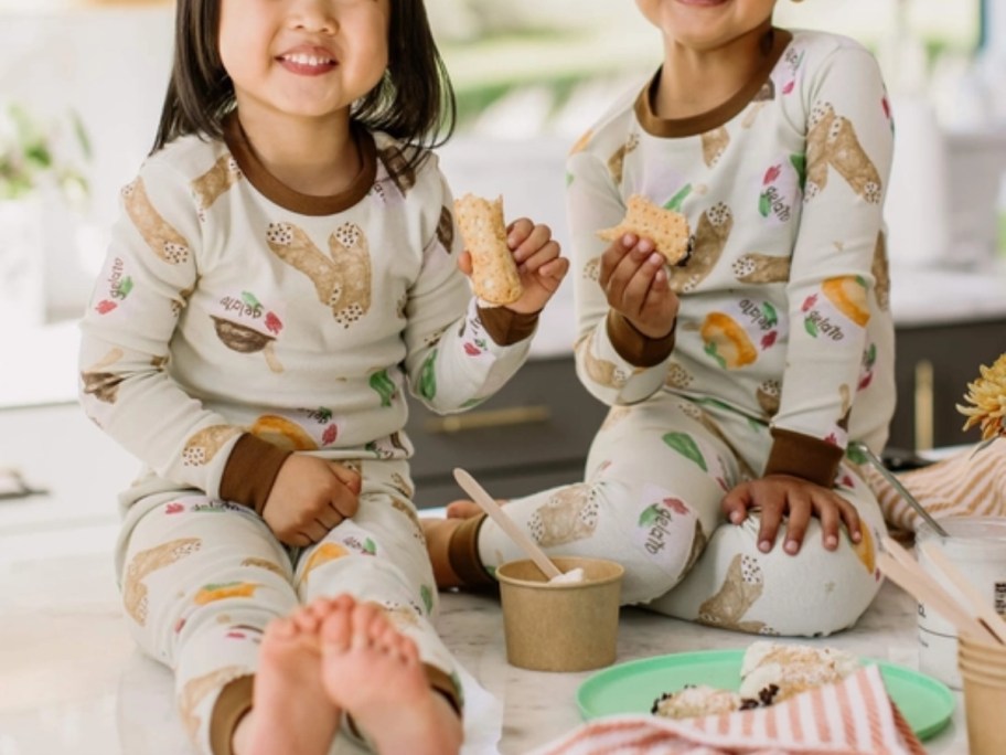 a little girl and boy wearing matching pajamas sitting on the floor