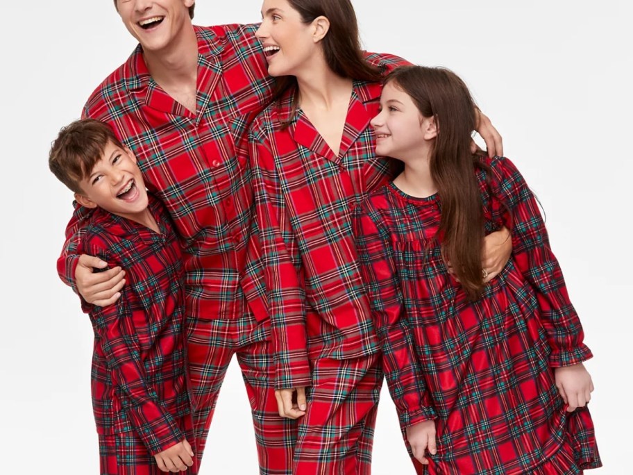 mom, dad, and kids wearing matching red plaid print Christmas pajamas