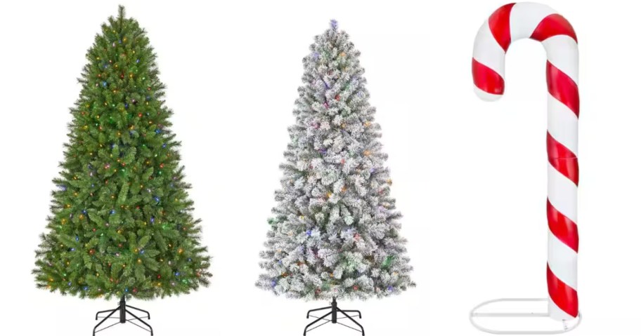 a tall green artificial Christmas tree with lights, a tall flocked white artificial Christmas tree with lights, and a tall red and white candy cane outdoor decor