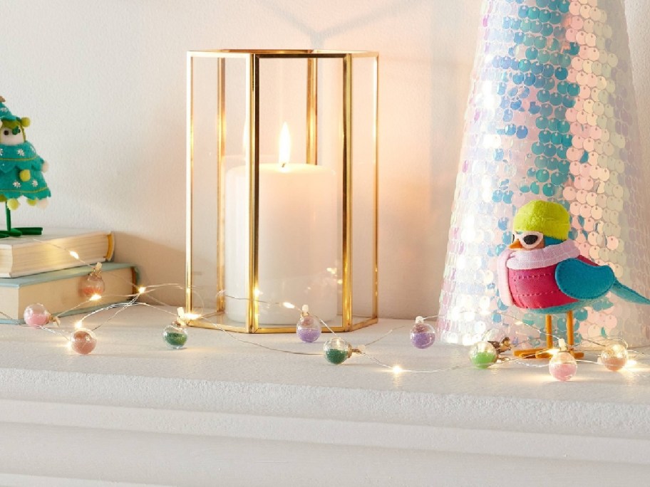 Confetti Globes Christmas Indoor String Lights displayed on the mantle with other decorations on other