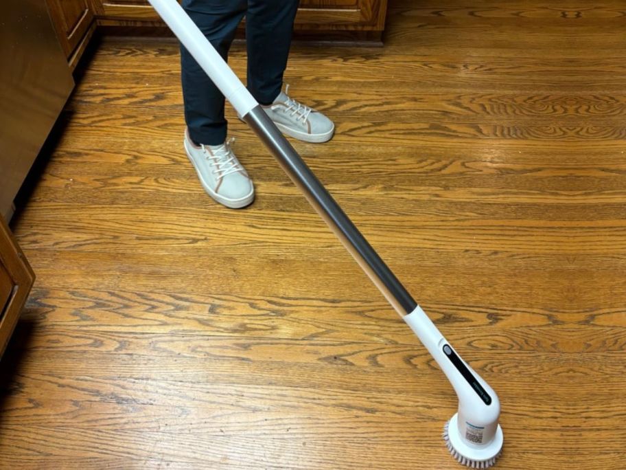 Man holding a cordless Spin Scrubber while standing on a hardwood floor