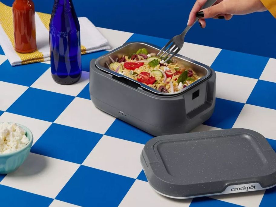 person using fork on food inside Crock-Pot GO Portable Food Warmer on picnic table