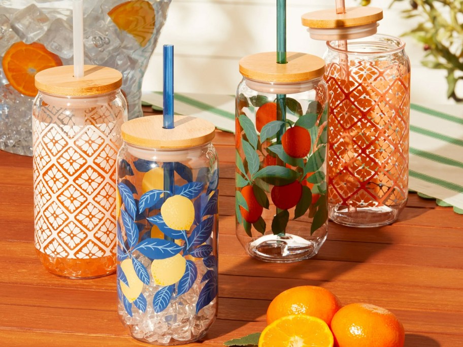 printed plastic can tumblers with wood lid and straws on table with oranges