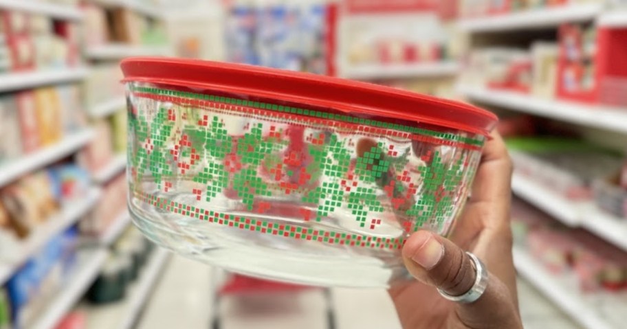hand holding a glass Pyrex containera with Christmas sweater design on it and a red lid 