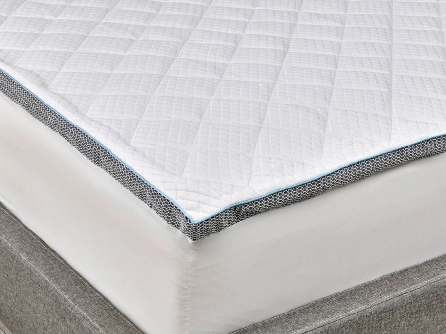 the corner of a mattress covered with a mattress topper