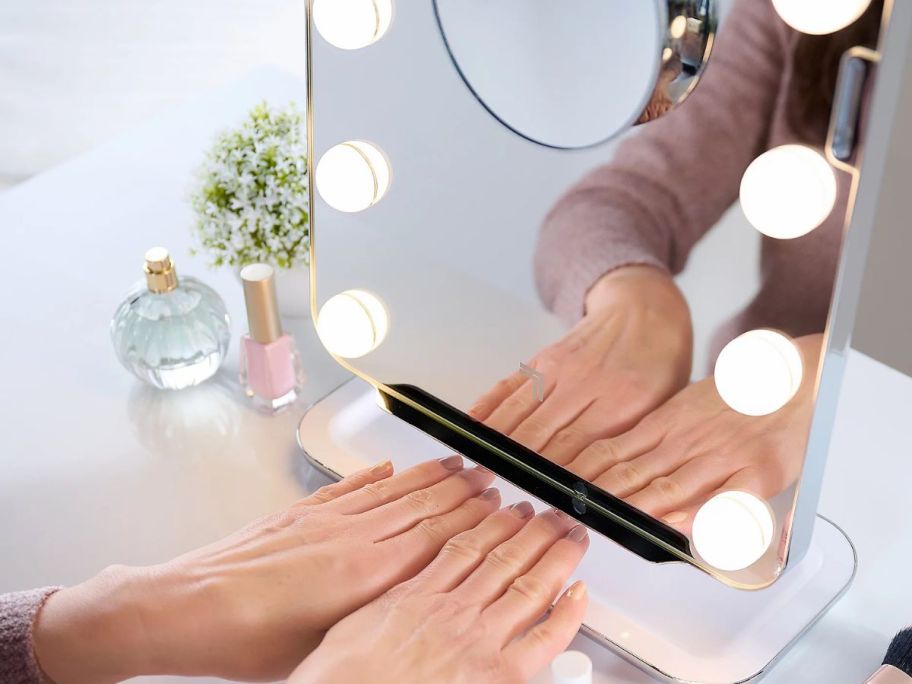 A woman drying her nails with her vanity mirror