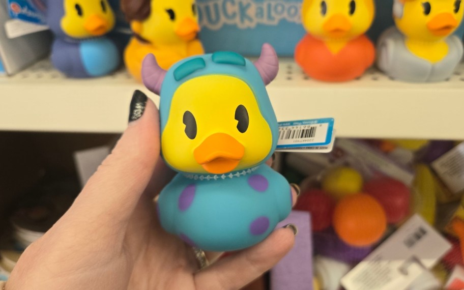 a womans hand holding a rubber duckie
