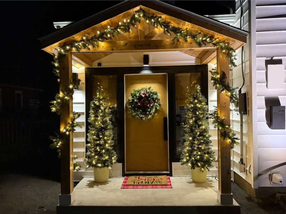 holiday decorated front door with lights and garland