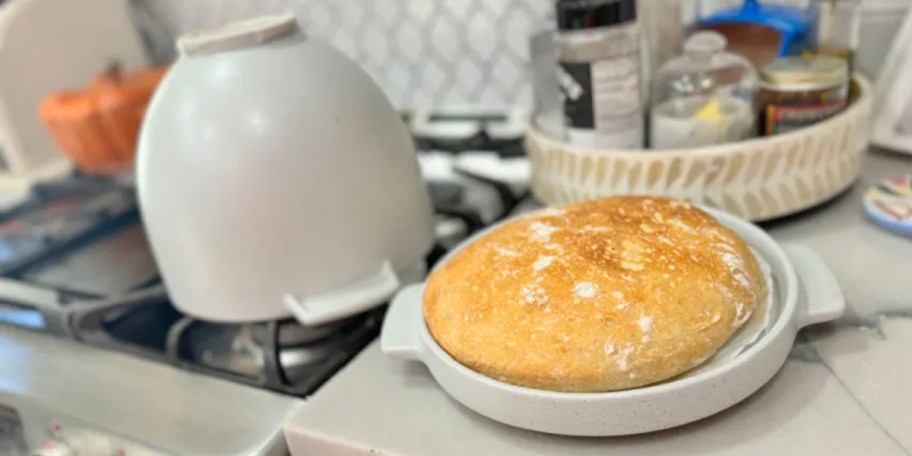 gray bread bowl with bread in lid sitting on counter