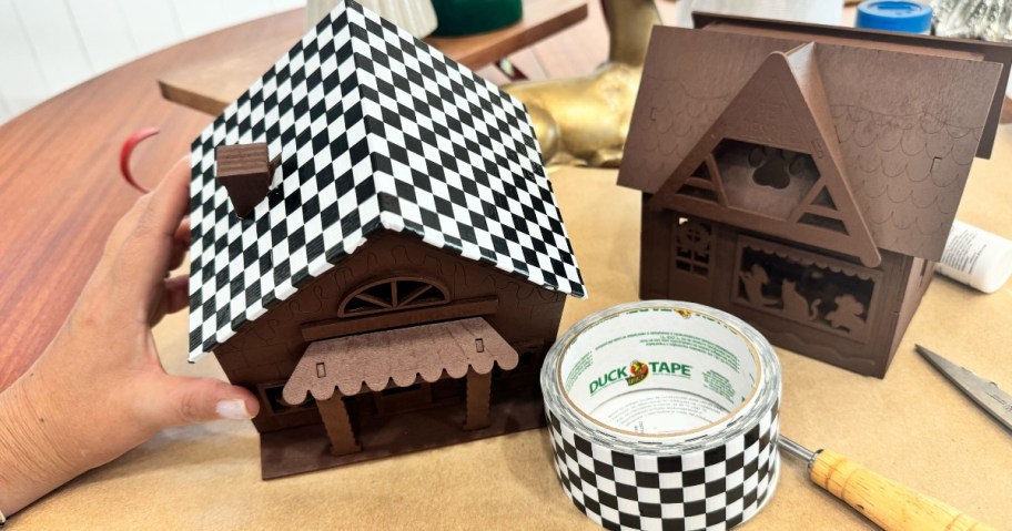 wooden craft houses that have been painted and started to be decorated with black and white duct tape and faux snow and other decor