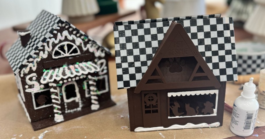 wooden craft houses that have been painted and started to be decorated with black and white duct tape and faux snow and other decor