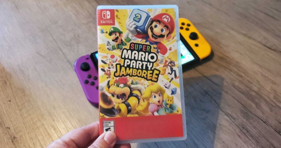 Super Mario Party Jamboree Video Game for Nintendo Switch in hand above switch console