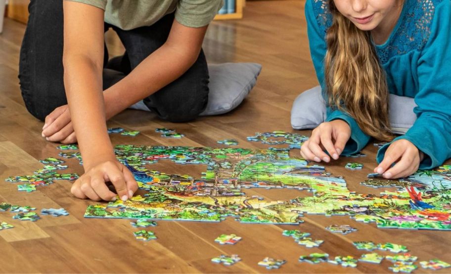 two kids putting a puzzle together while seated on the floor