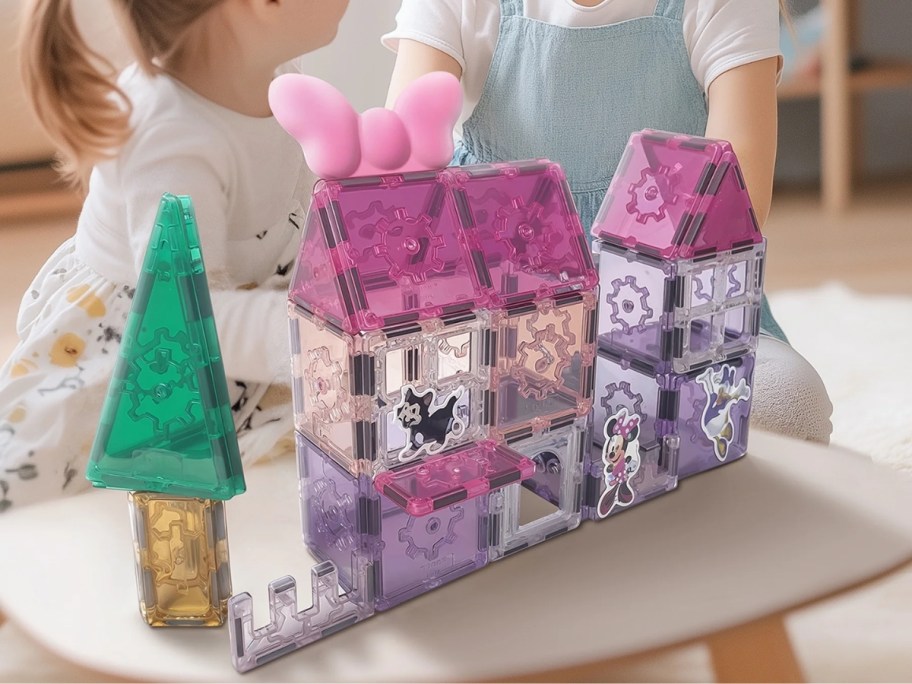 two little girls playing a pink and purple magnetic tiles set that is Minnie Mouse themed