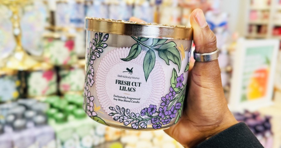 hand holding up a lilac scented 3-wick candle