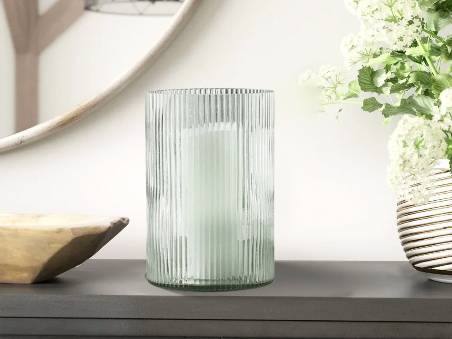 ribbed glass candle holder on table near other decor