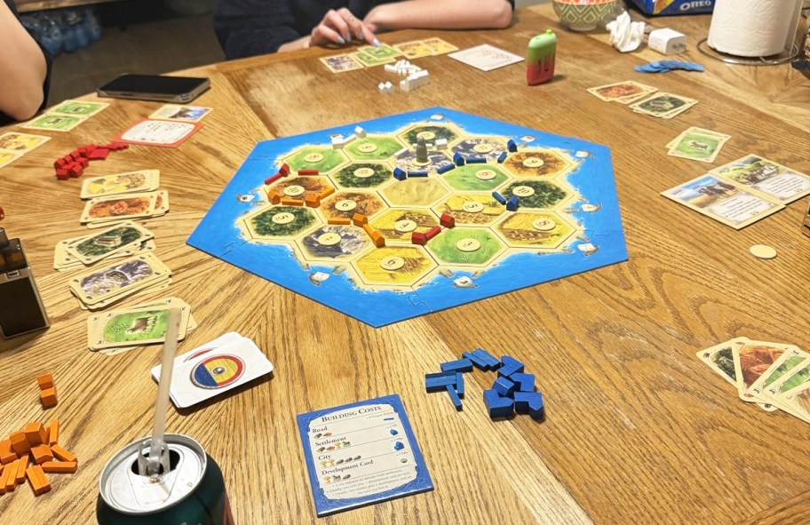 people playing CATAN game on wood table