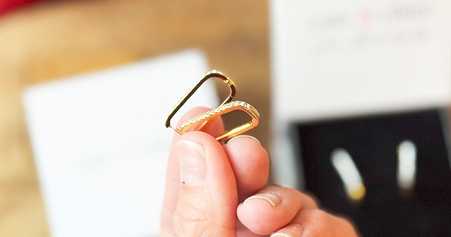 hands holding gold square hoop earrings